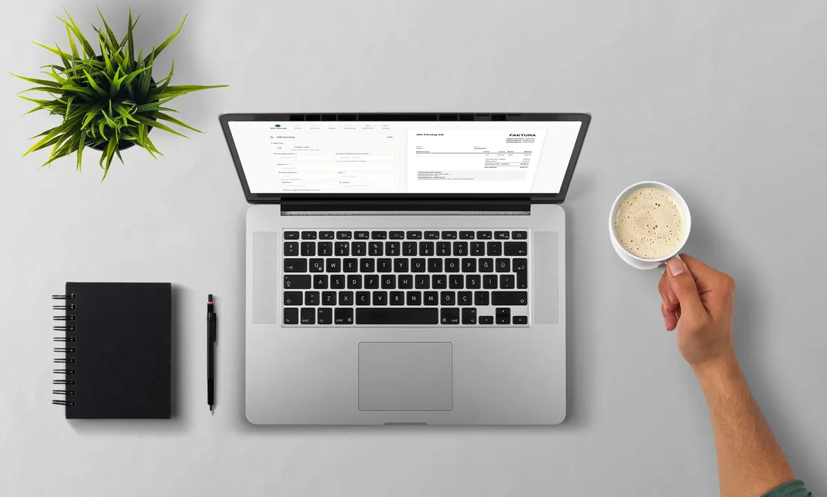 Laptop på ett skrivbord med en faktura öppnad på skärmen, bredvid en kopp kaffe, anteckningsbok och en krukväxt.